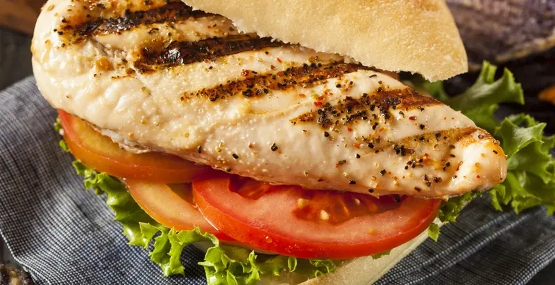 ساندویچ مرغ گریل شده همراه با گوجه‌فرنگی و کاهو در نان پیتا