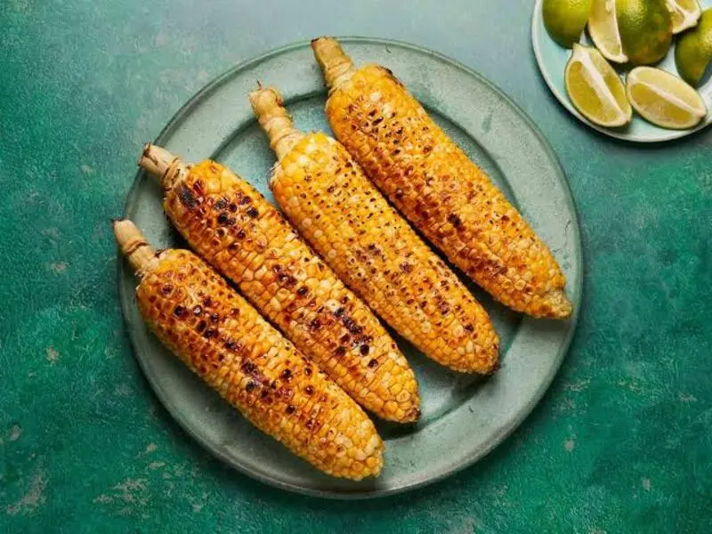 ذرت کباب شده (Grilled Corn) روی یک بشقاب سبز رنگ