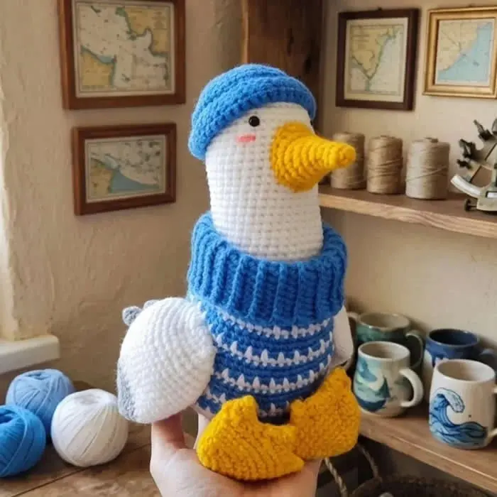 عروسک بافتنی (Amigurumi) با کلاه و لباس آبی و پاهای زرد
