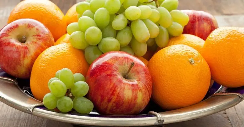 میوه تازه شامل سیب و انگور و پرتقال در یک ظرف نقره‌ای