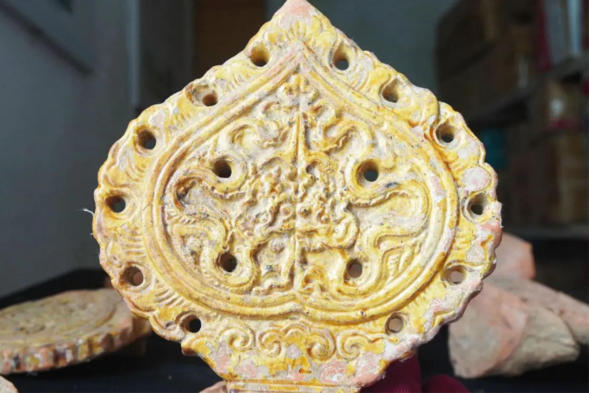 نمای نزدیک از یک قطعه تزیینی باستانی به شکل برگ بودی با حاشیه‌های سوراخ‌دار و نقوش برجسته و پیچیده