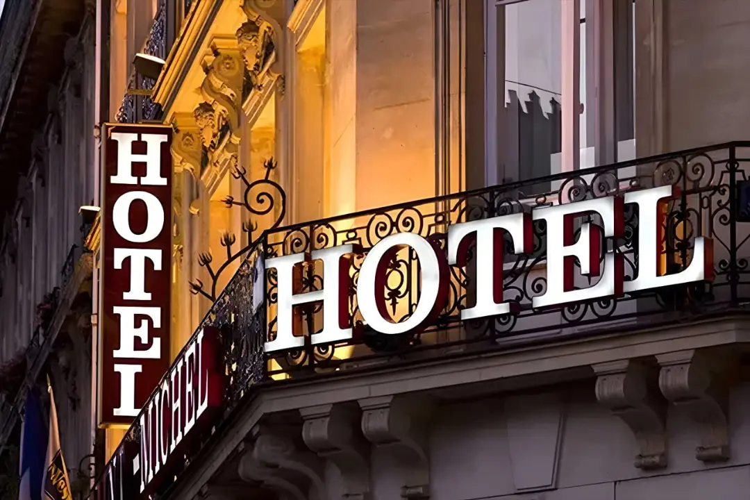 تابلوی درخشان هتل (Hotel) روی بالکن یک ساختمان قدیمی