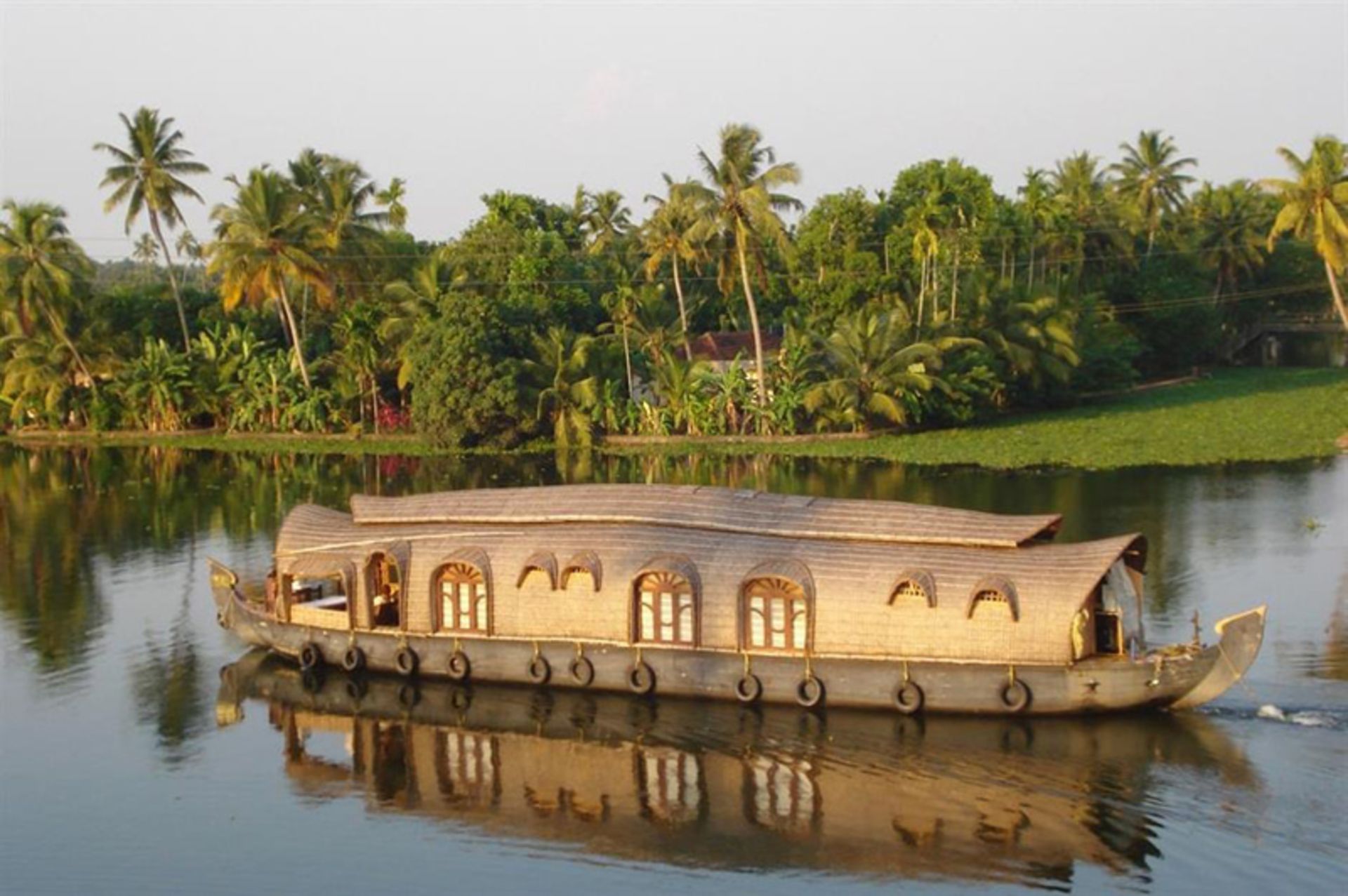 خانه قایقی در رودخانه ای با مناظر سبز در هند