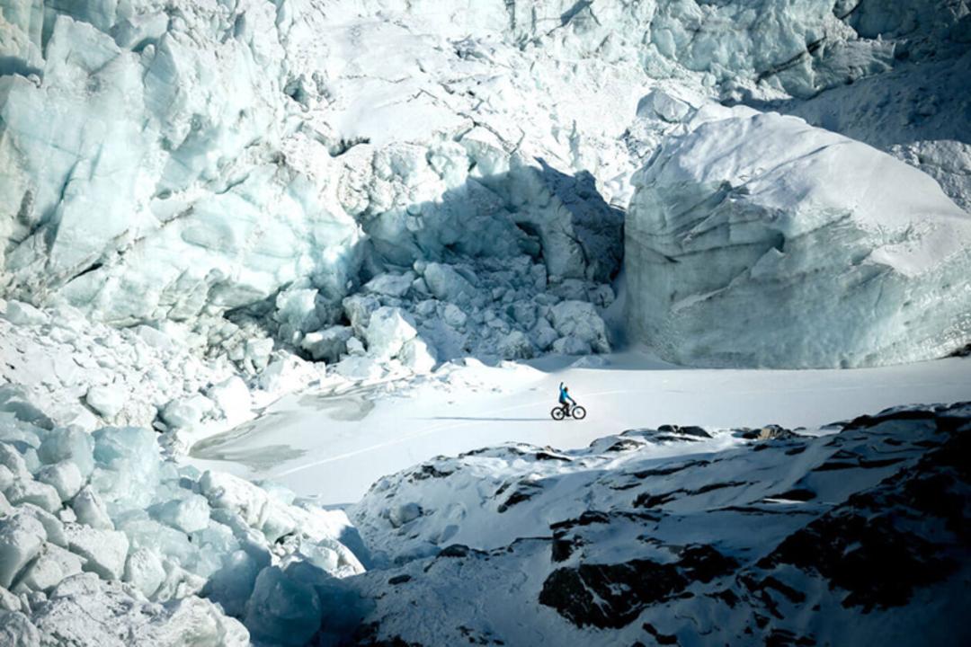فردی با دوچرخه میان برف کوهستان