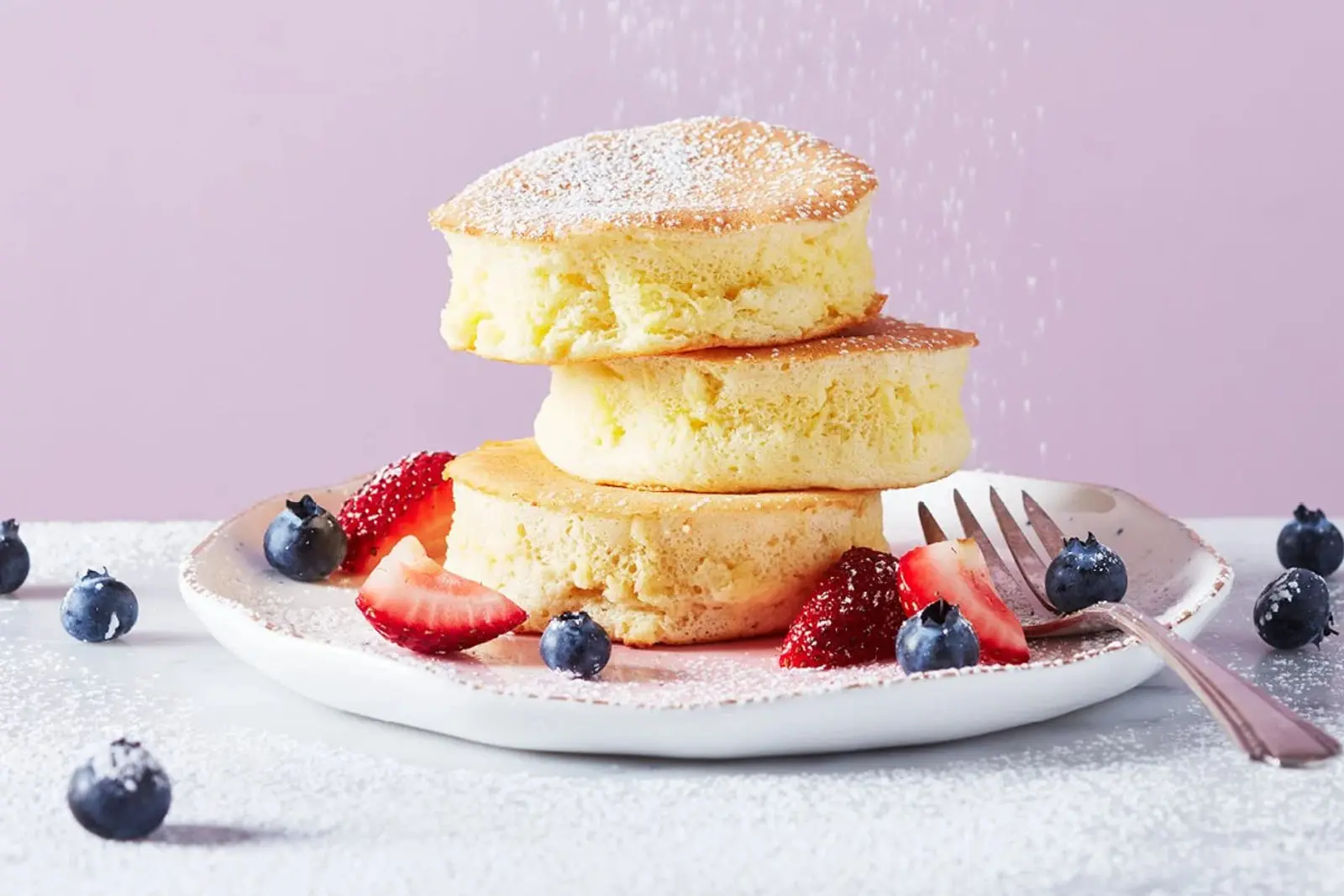پنکیک ژاپنی (Japanese Pancake) روی بشقاب همراه با توت‌فرنگی و بلوبری