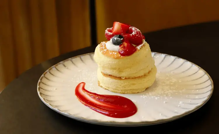 پنکیک ژاپنی (Japanese Souffle Pancake) روی بشقاب همراه با خامه و توت فرنگی