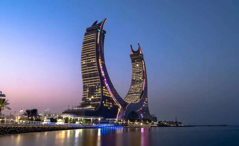هتل جیمارا (Jumeirah) با معماری منحنی در کنار ساحل در شب