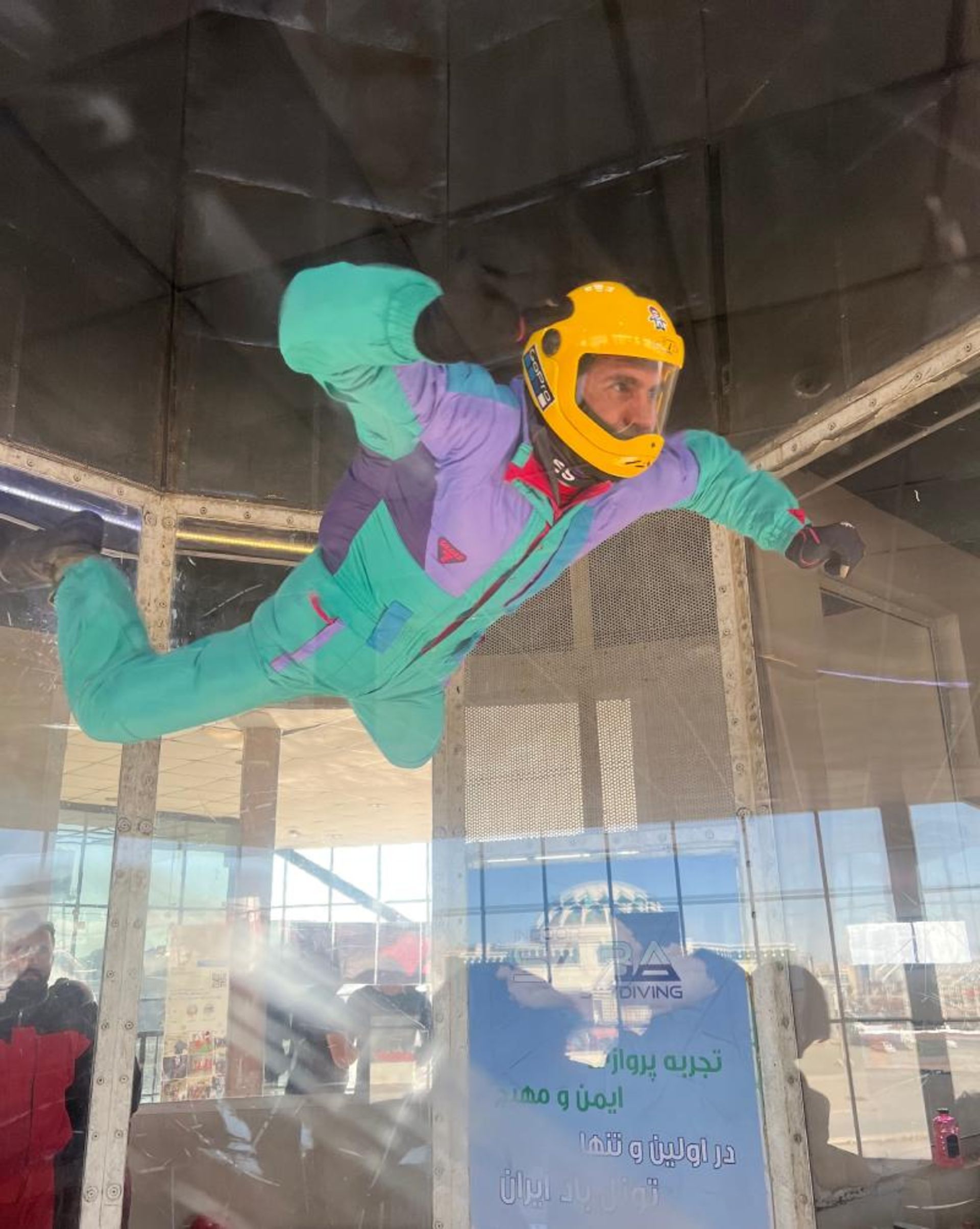 فردی با لباس مخصوص معلق در تونل باد صبا مشهد