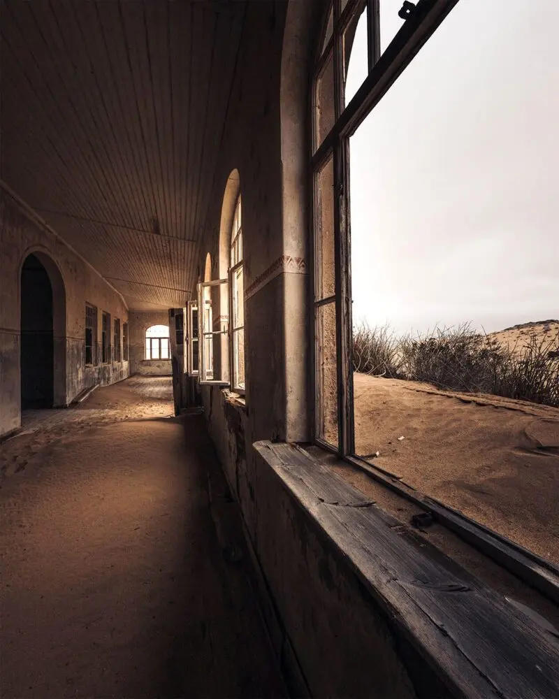 اتاق متروکه در شهر ارواح کولمانسکوپ (Kolmanskop) با شن‌های روان در پنجره