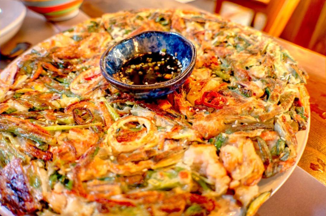 پنکیک کره‌ای (Pajeon) با سبزیجات و سس سویا در یک بشقاب