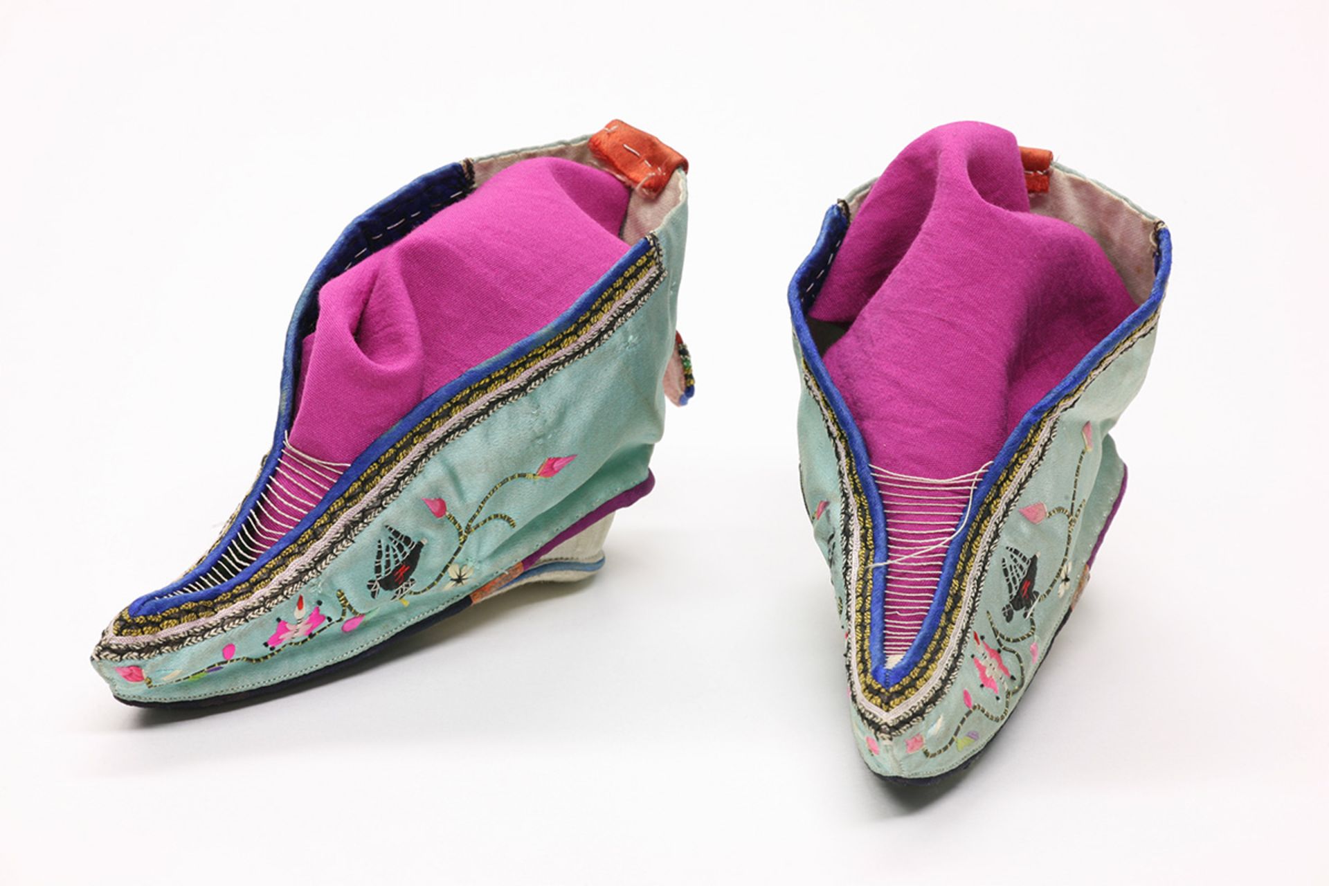 نمای نزدیک از یک جفت کفش ابریشمی «لوتوس» با رنگ آبی روشن و لایه‌های بنفش در داخل