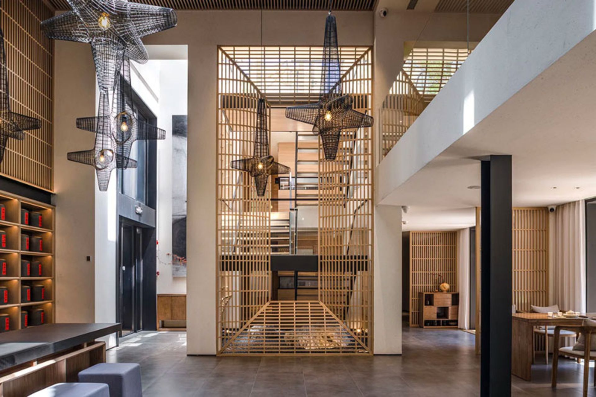 نمای داخلی دو طبقه چایخانه دریاچه آبی با لوسترهای مشبک و قفسه‌بندی چوبی