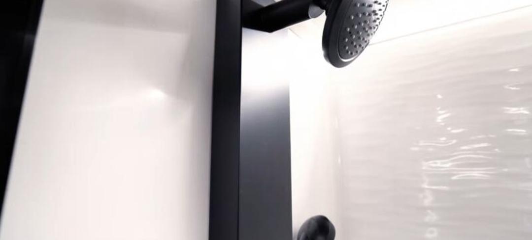 دوش سیاه رنگ در کابین حمام تریلر مسافرتی با دیواره سفید