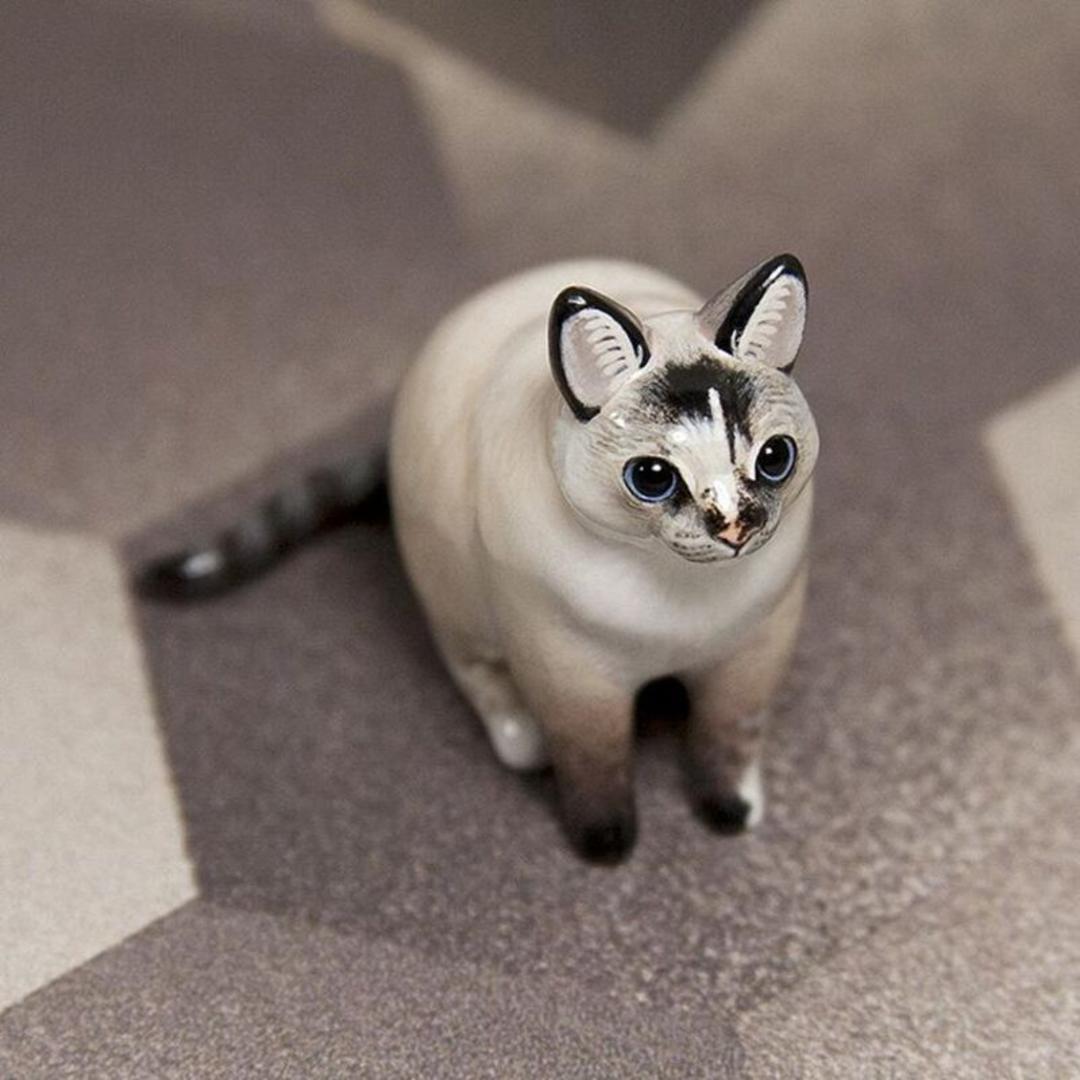 مجسمه مینیاتوری گربه سیامی (Siamese cat) با جزئیات دقیق روی سطح صاف