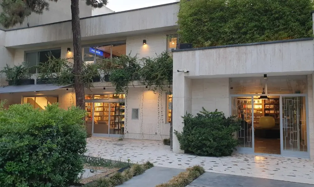 نمای بیرونی ساختمان مدرن کتابفروشی ایرانشهر با دیوارهای سنگی و گیاهان سبز