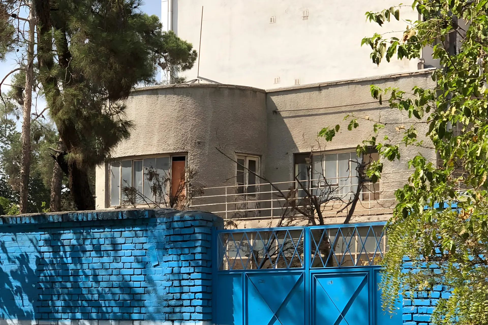 ساختمان قدیمی با معماری مدرن و دیواری آبی رنگ در تهران