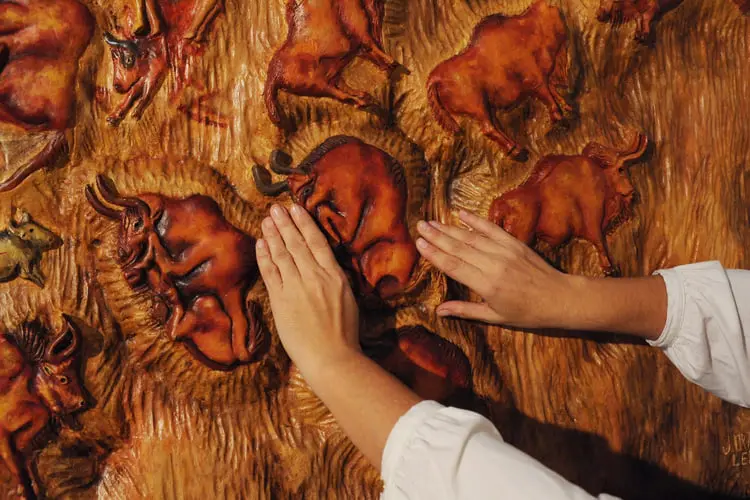 مجسمه برجسته (Relief) از حیوانات که دست فردی روی آن قرار دارد