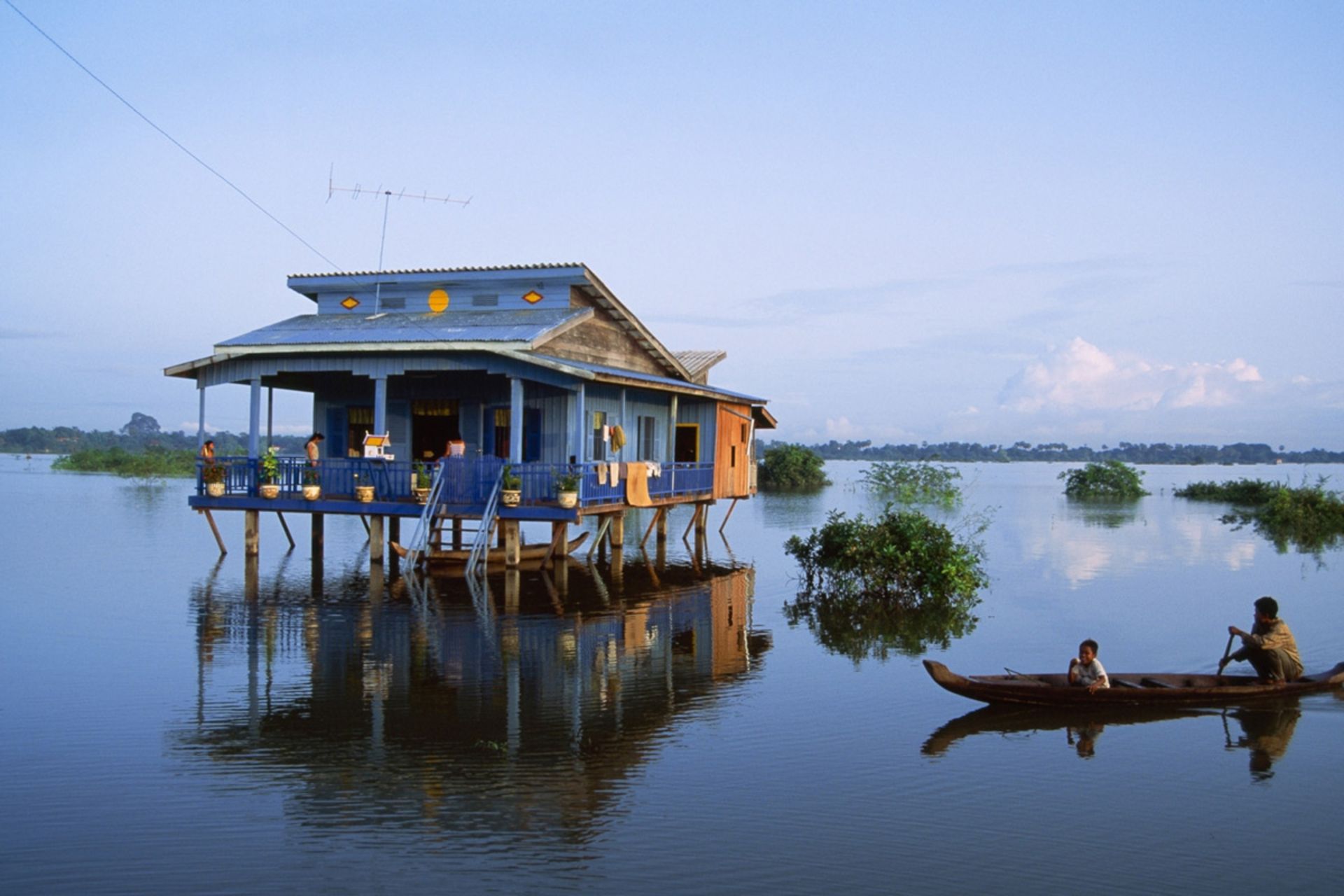 قایقی در آب و کنار خانه پایه دار