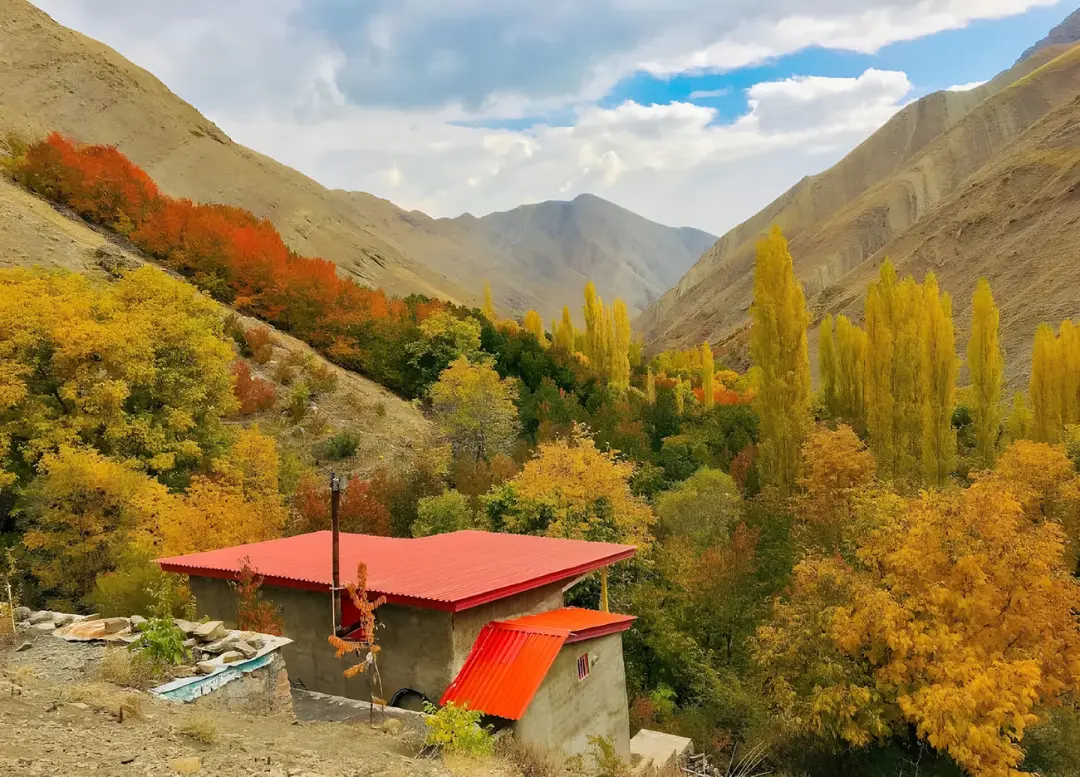 دره پاییزی با درختان رنگارنگ و کوه‌های مرتفع در روستای آهار