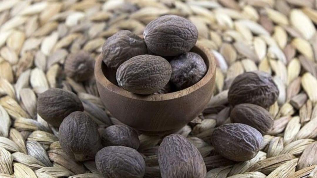 دانه های جوز هندی (Nutmeg) در یک ظرف چوبی کوچک