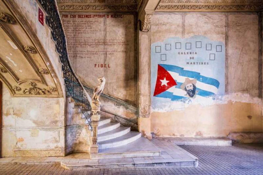 دیوار قدیمی با نقاشی پرچم کوبا (Cuba) و نوشته‌های تاریخی در فضای معماری کلاسیک