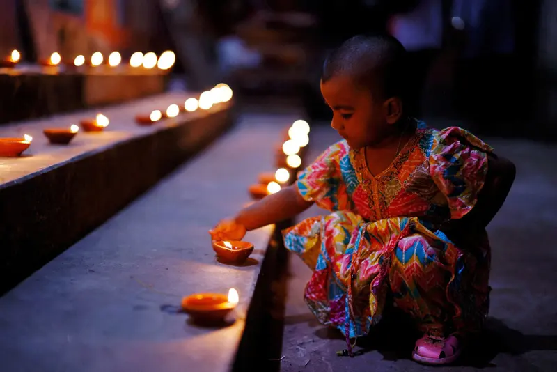 کودکی کنار شمع  های روشن جشن دیوالی
