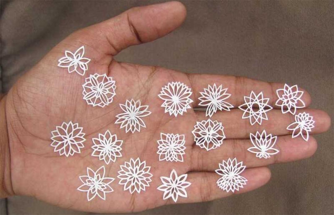 گل‌های کاغذی سفید با طرح‌های هندسی و گل‌مانند روی کف دست