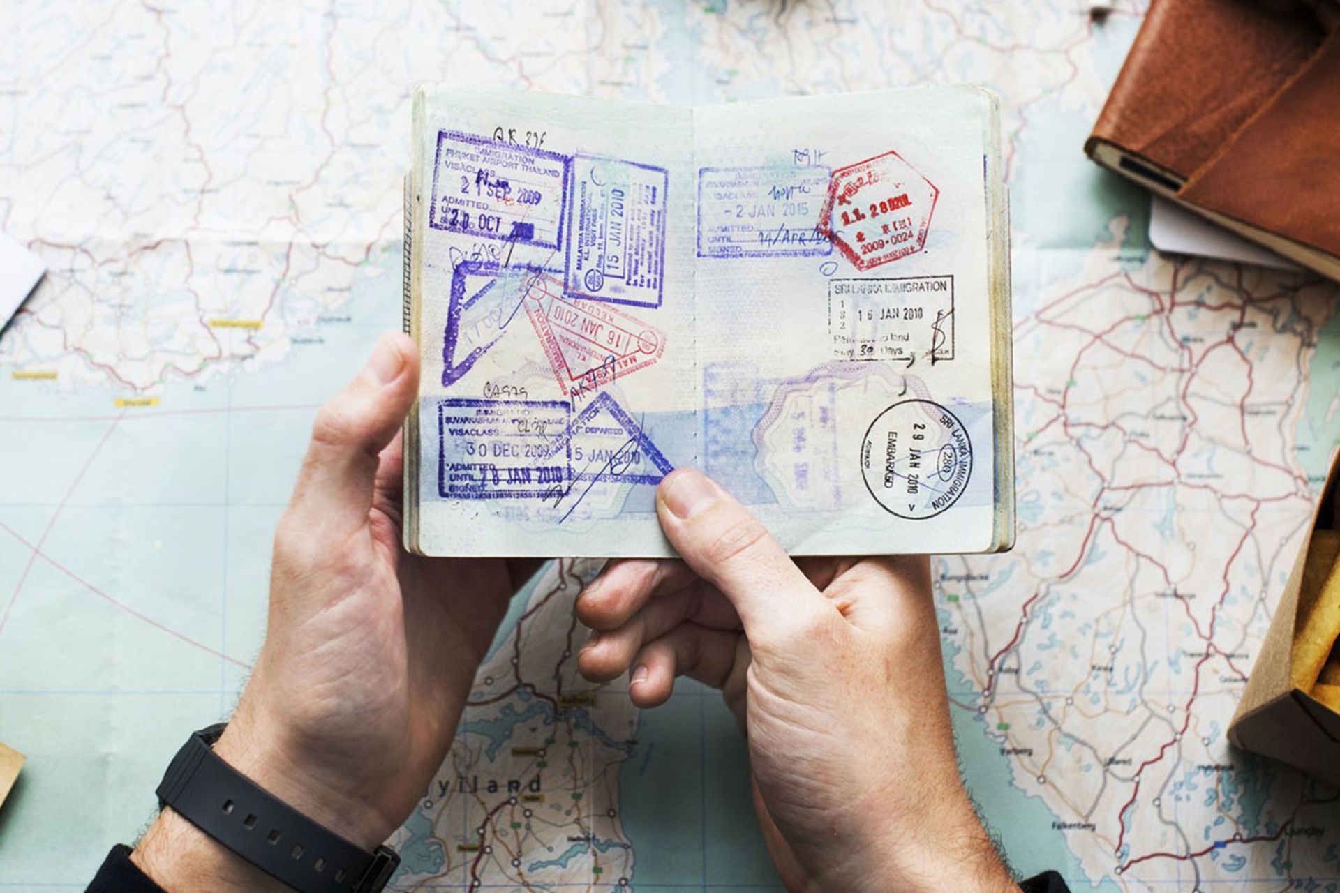 گذرنامه‌ای با مهرهای رنگارنگ بر روی نقشه سفر