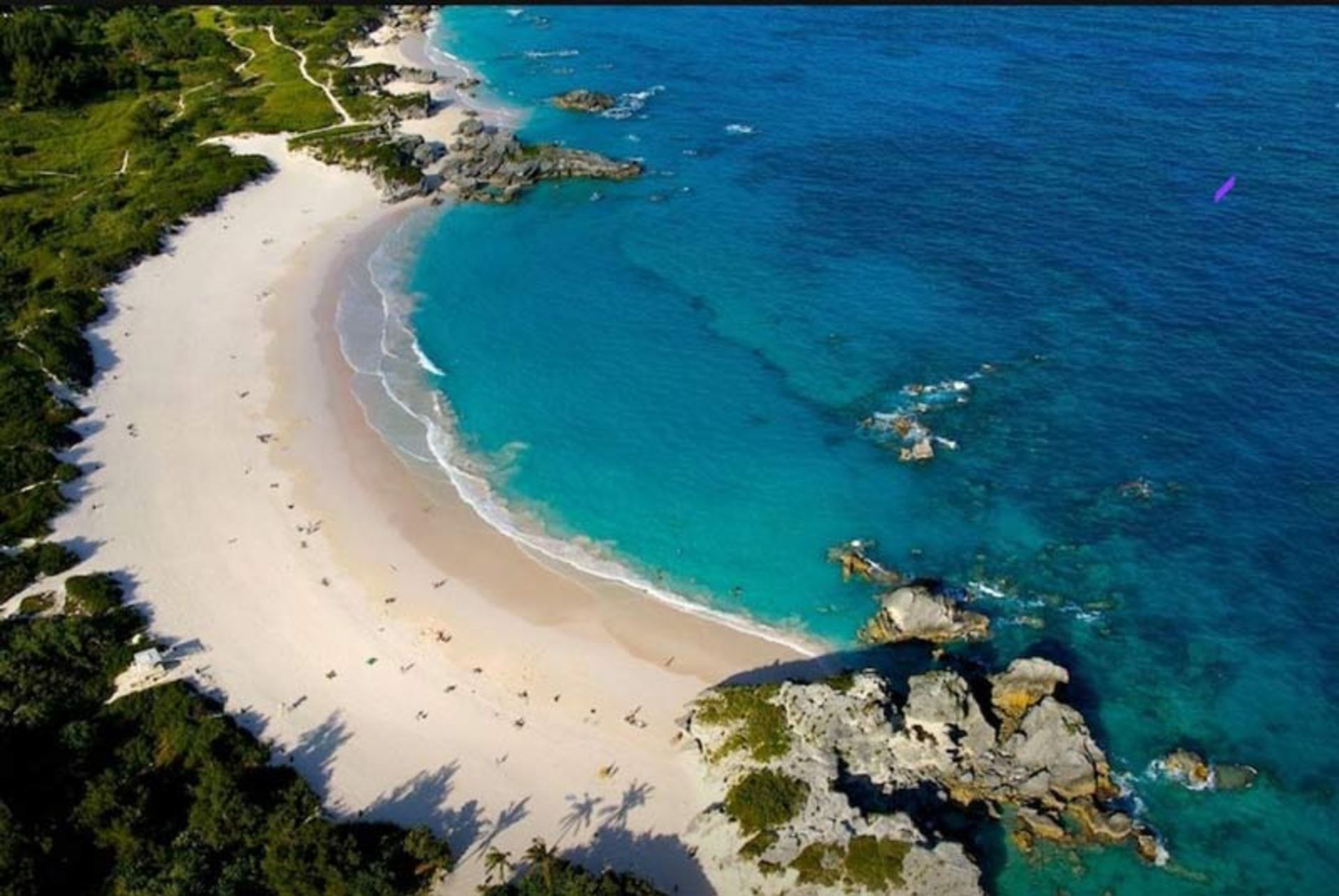 نمای پانوراما و هوایی از ساحل مشهور خلیح هورس‌شو در برمودا با شن‌های سفید و صخره‌های نمادین