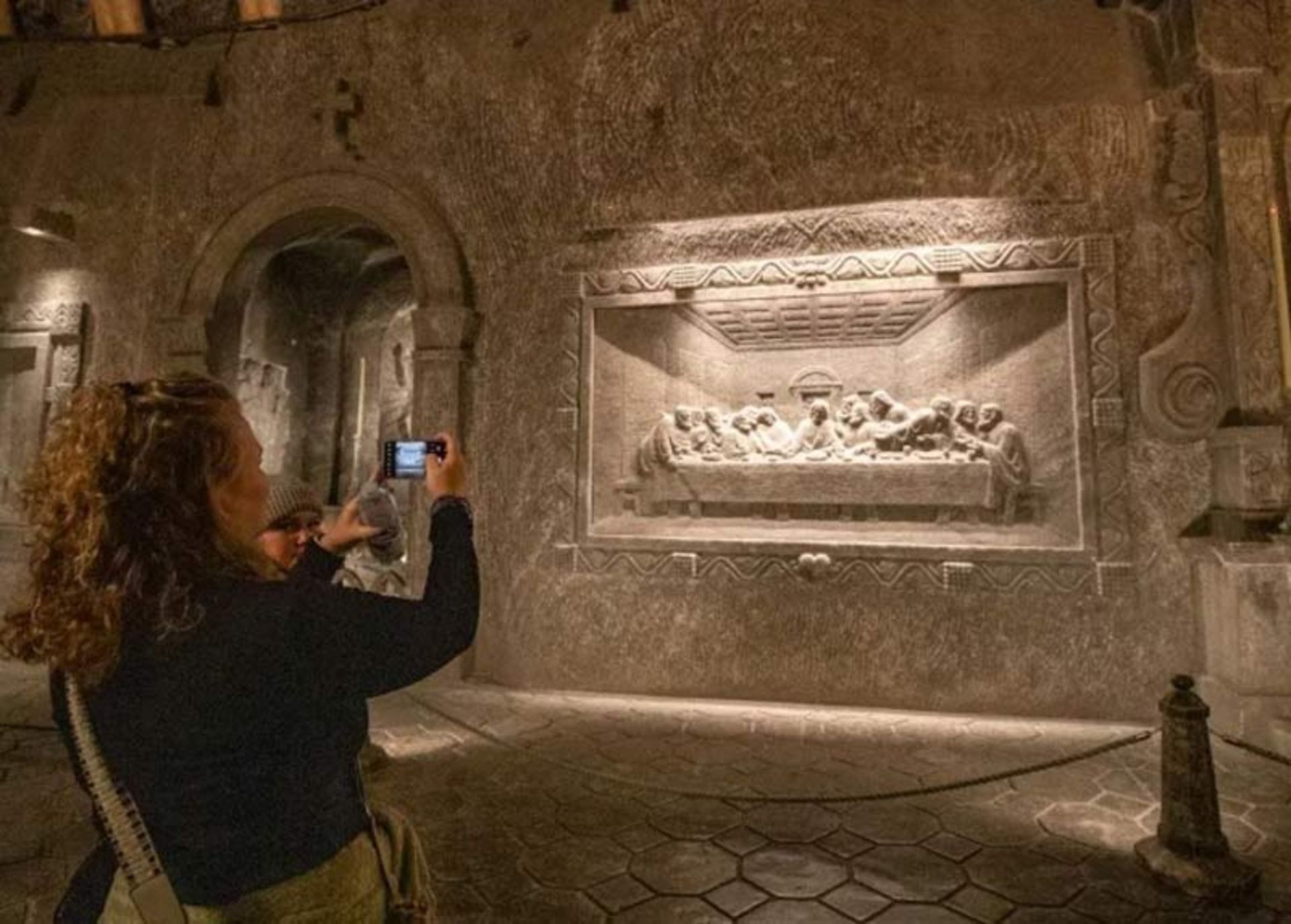 گردشگری در حال عکاسی از نقش‌برجسته نمکی شام آخر بر دیوار معدن ویلیچکا