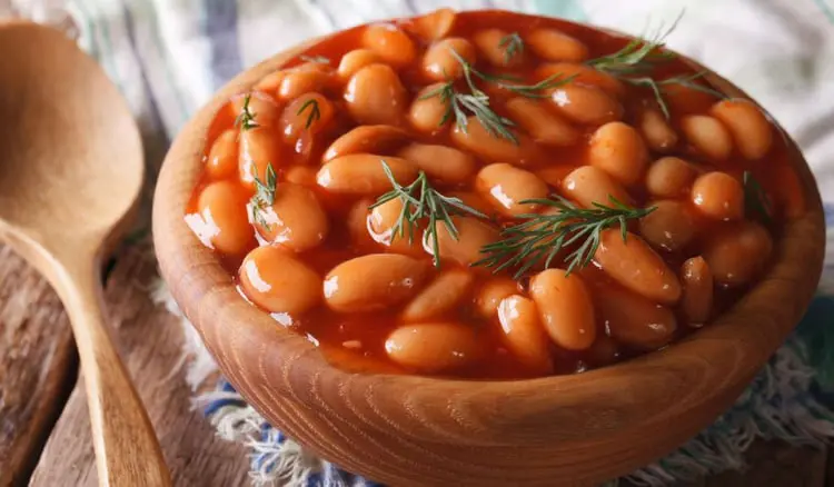 خوراک لوبیا چیتی با سس گوجه‌فرنگی و گیاه شوید در ظرف چوبی