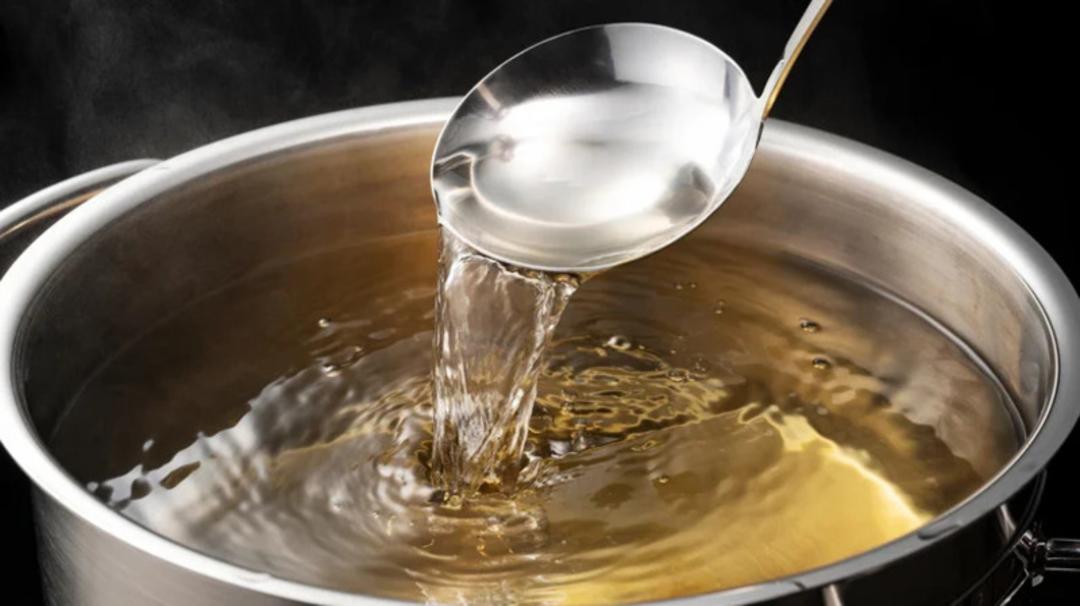 سوپ داغ هات پات (Hot Pot) در حال ریخته شدن با ملاقه در قاب پخت