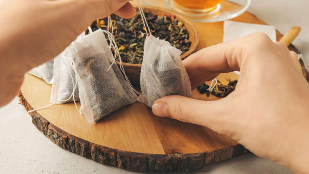 چای کیسه‌ای گیاهی در حال چیده شدن روی تخته چوبی