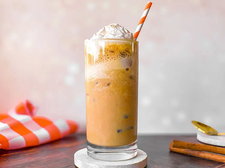 پامکین اسپایس لاته (Pumpkin Spice Latte) با خامه و نی در لیوان بلند