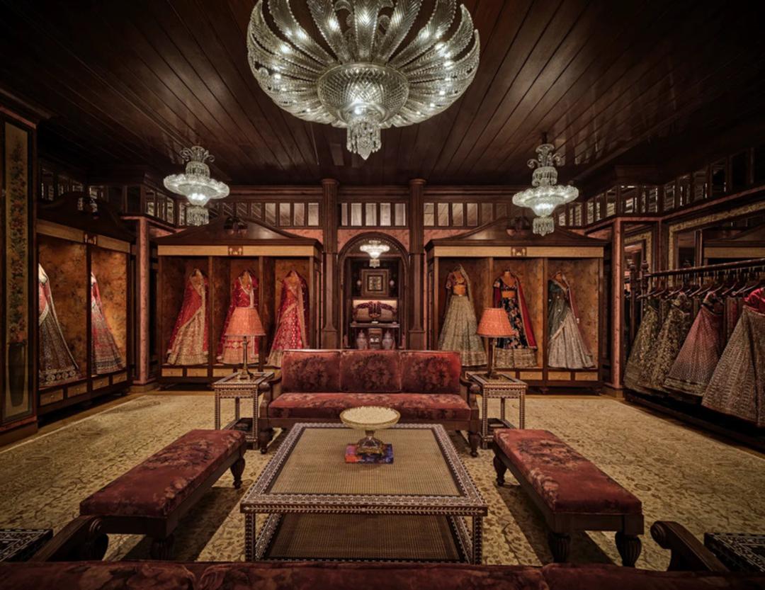 نمای داخلی فروشگاه سابیاساچی (Sabyasachi) با لوستر بزرگ و لباس‌های سنتی