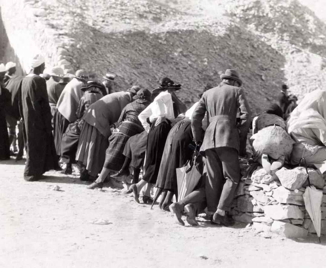  بازدیدکنندگان اروپایی در حال خم شدن روی لبه سنگی برای تماشای داخل مقبره توت‌عنخ‌آمون