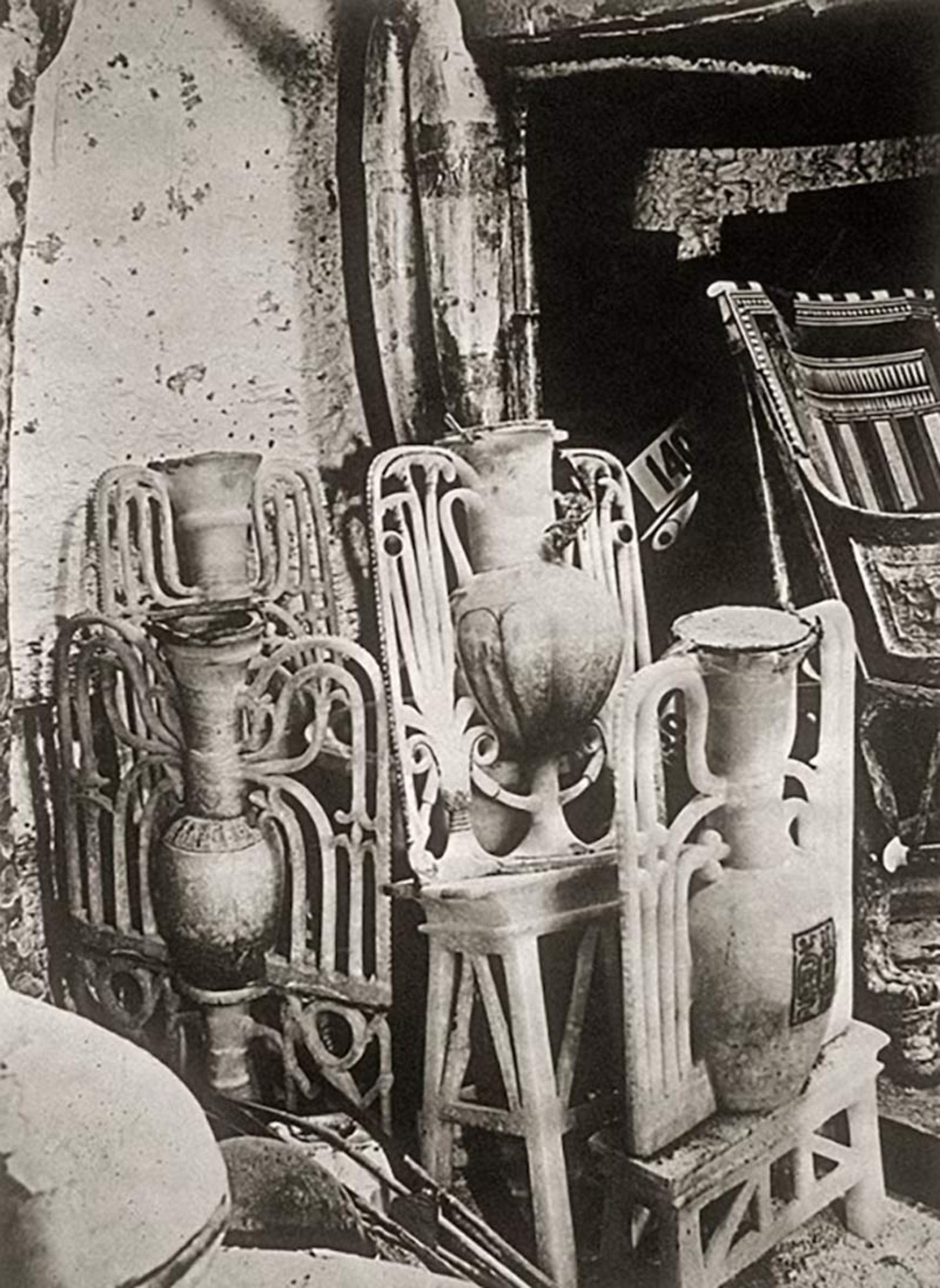 چیدمان اشیاء تدفینی شامل گلدان‌های مرمرین ظریف و صندلی‌های چوبی شماره‌گذاری شده