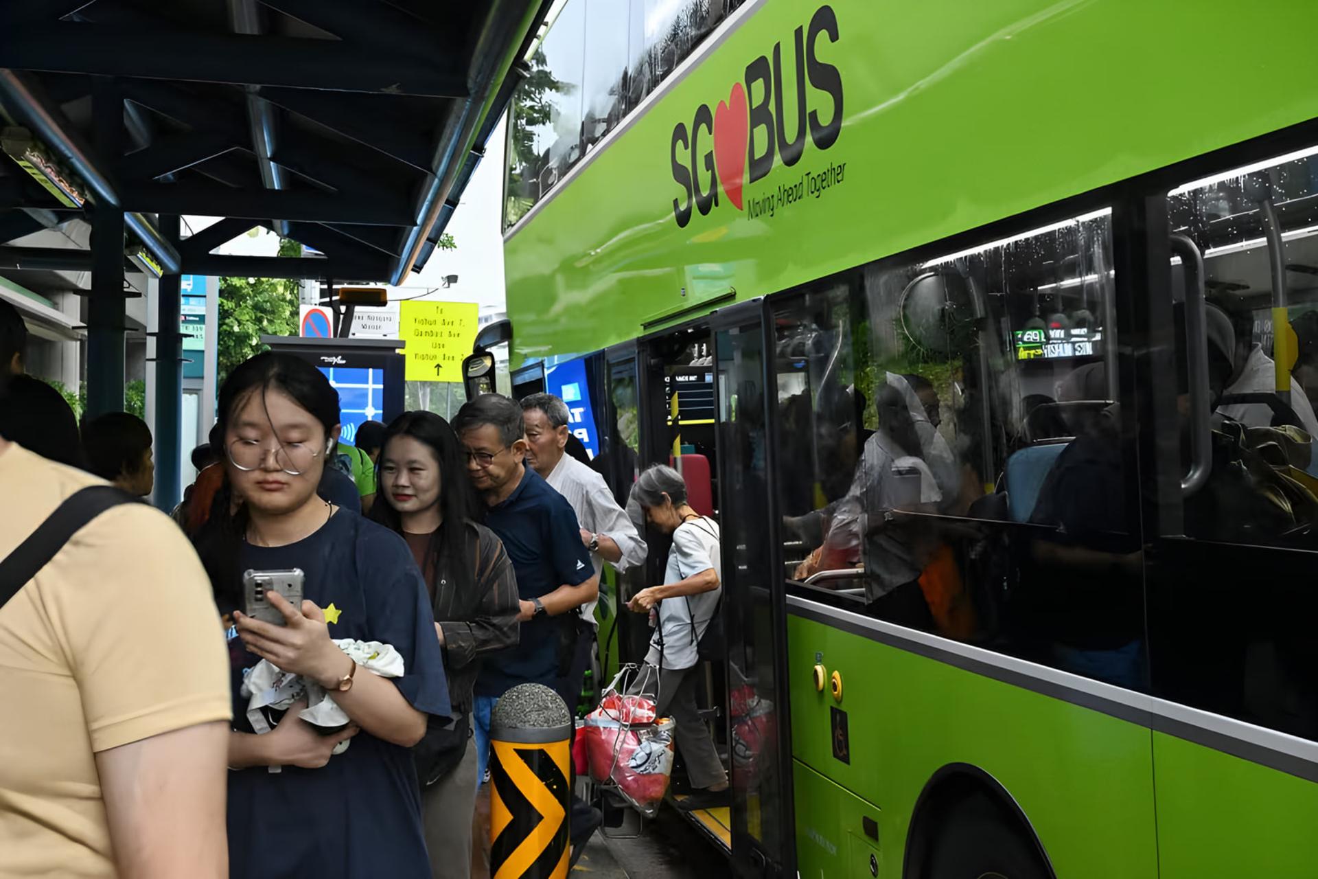 مسافران در حال سوار شدن به اتوبوس سبز رنگ (SG Bus) در سنگاپور