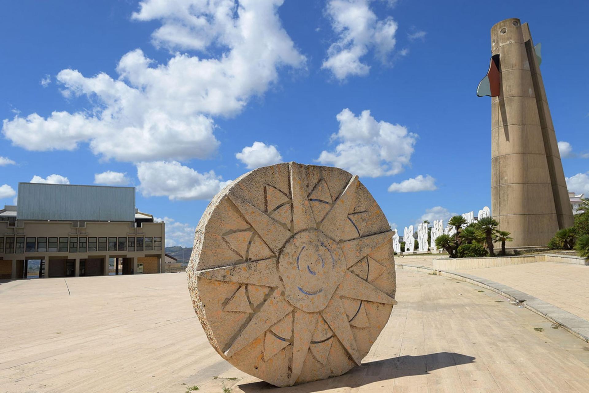 مجسمه خورشید و یک برج سیمانی با بالهای رنگی در شهر سیسیل