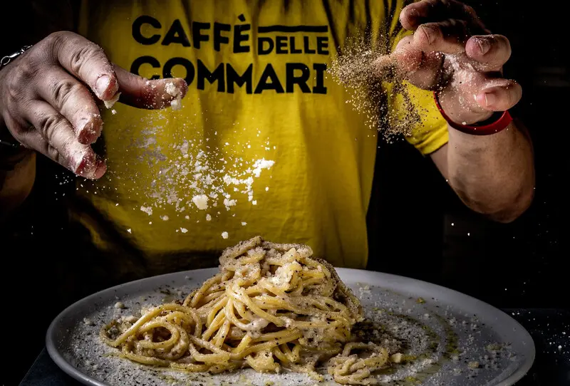 پاشیدن پنیر پودری روی بشقاب پاستای کربونارا (Carbonara)