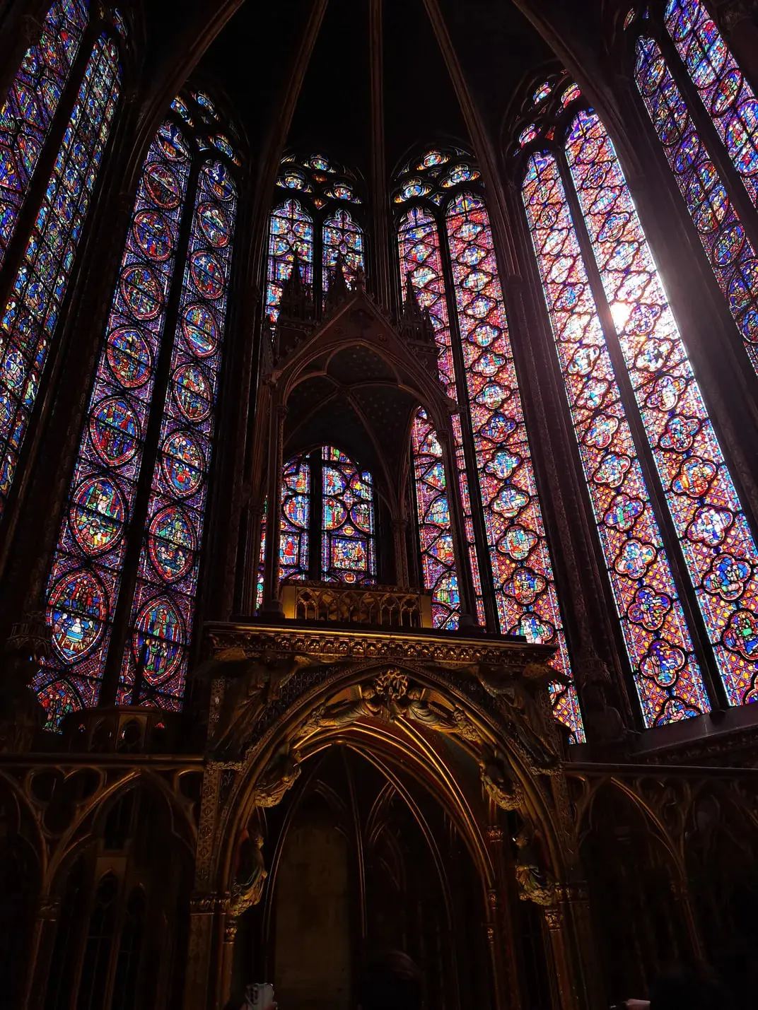 پنجره‌های رنگی (Stained Glass) با طرح‌های هندسی و مذهبی در فضای داخلی کلیسا
