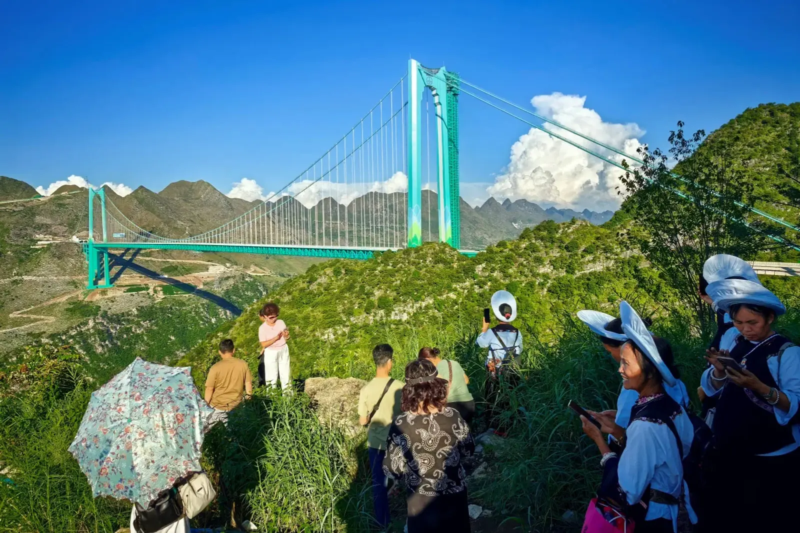 پل معلق (Suspension Bridge) بزرگ و سبز رنگ میان کوه‌های مرتفع
