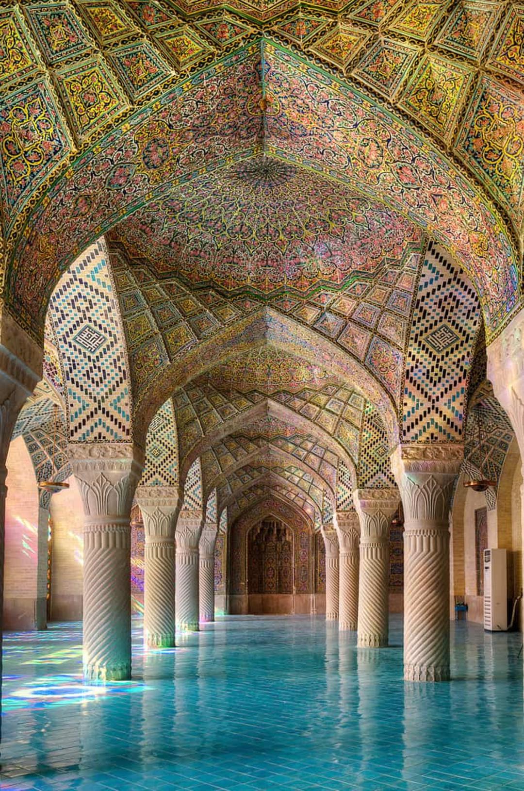 کاشی‌کاری‌های رنگارنگ و نورهای منعکس شده بر کف آبی‌رنگ مسجد
