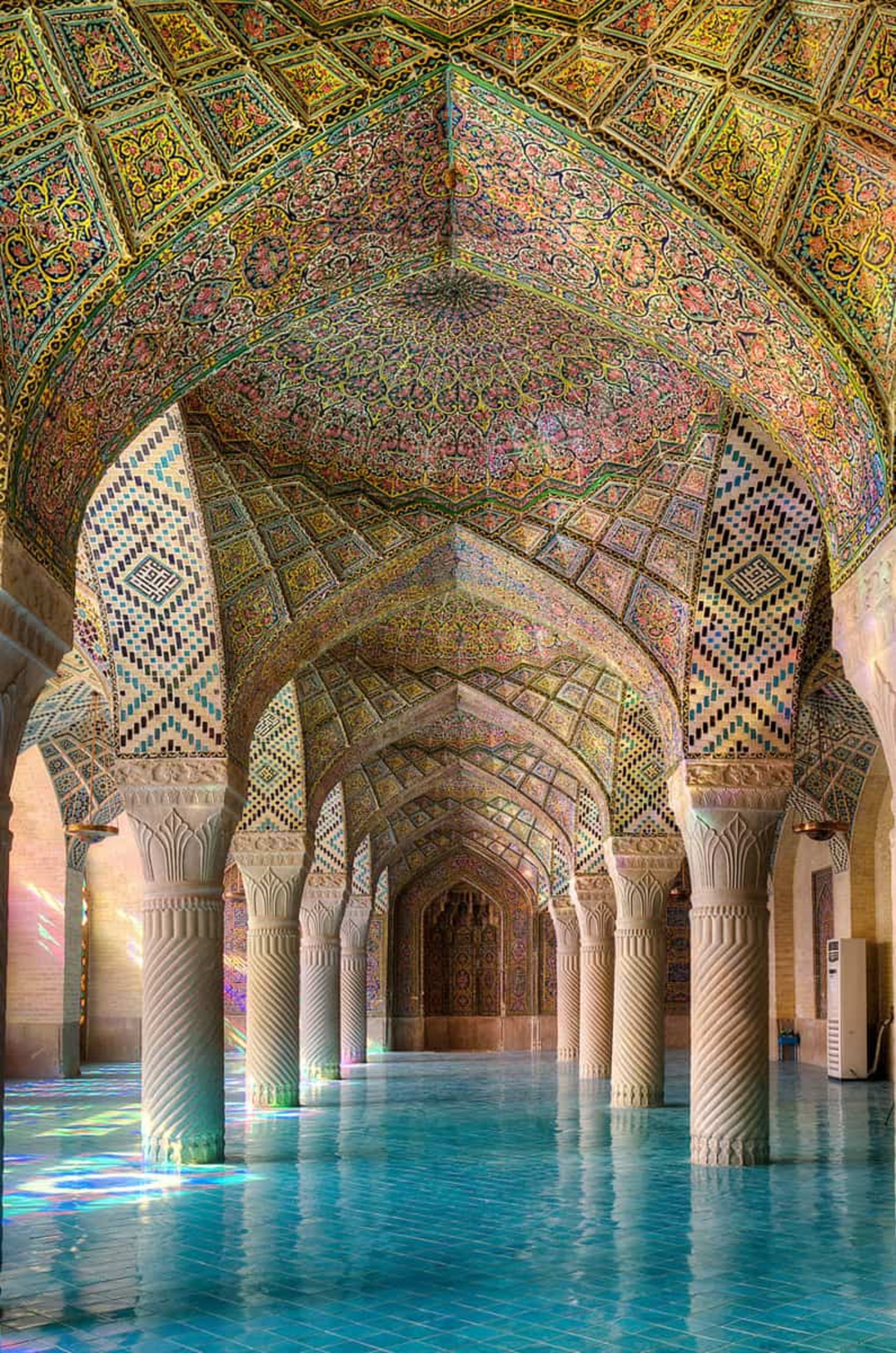 کاشی‌کاری‌های رنگارنگ و نورهای منعکس شده بر کف آبی‌رنگ مسجد