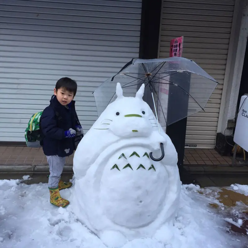 مجسمه آدم‌برفی شخصیت توتورو (Totoro) در کنار یک کودک در برف