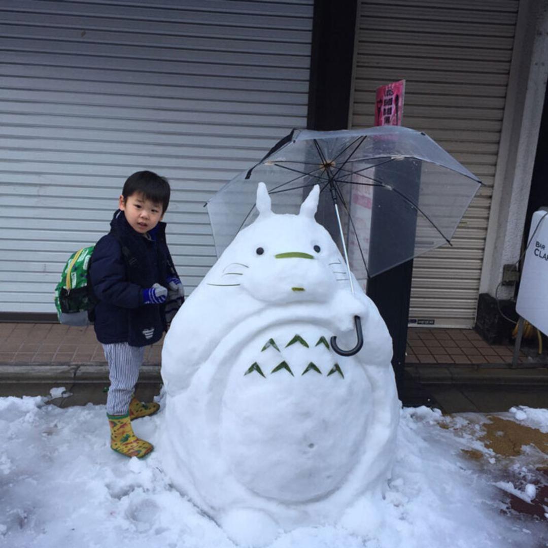 مجسمه آدم‌برفی شخصیت توتورو (Totoro) در کنار یک کودک در برف