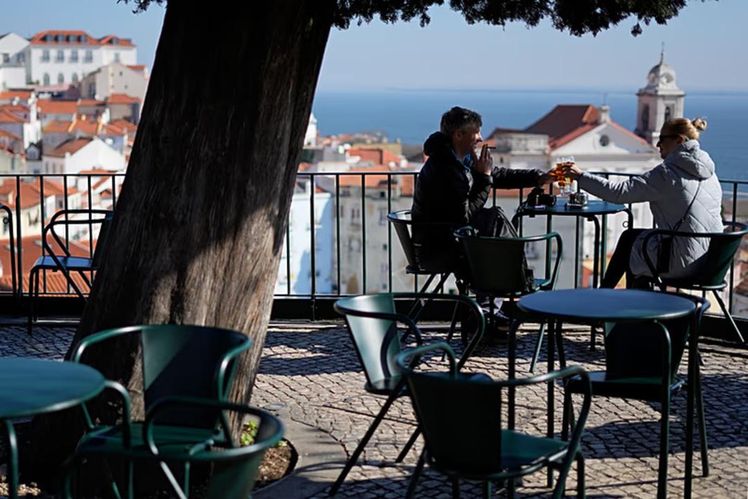 دو نفر در کافه ای با منظره شهر لیسبون (Lisbon) نشسته‌اند