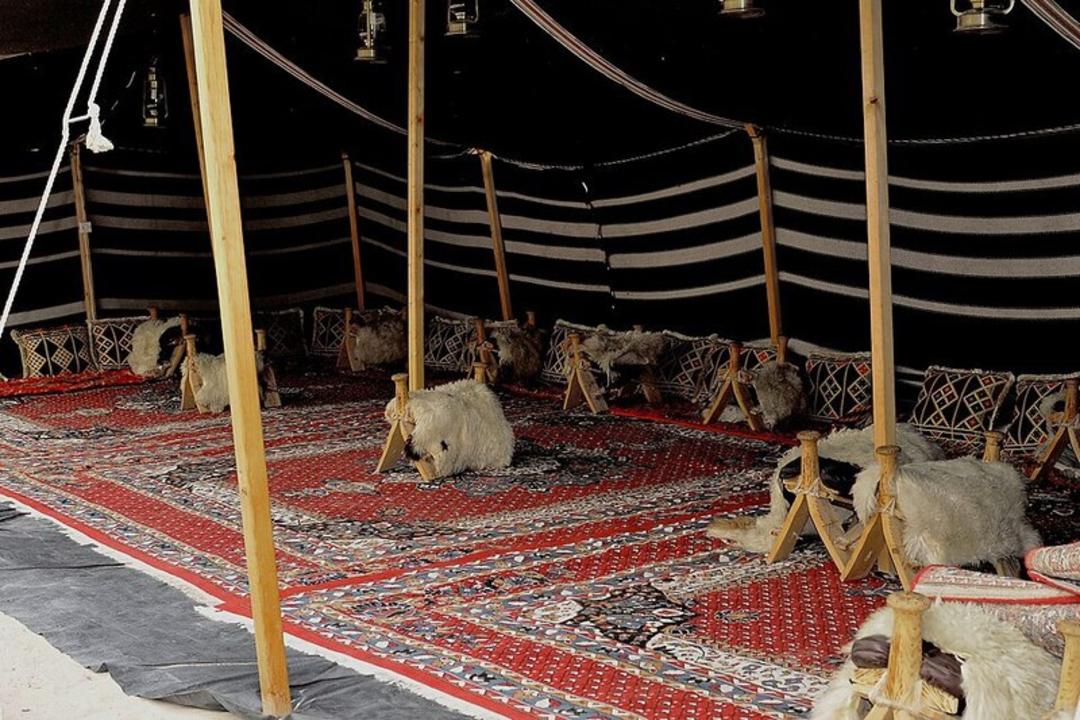 خیمه سنتی با فرش‌های قرمز و کوه‌های پشمی برای نشستن