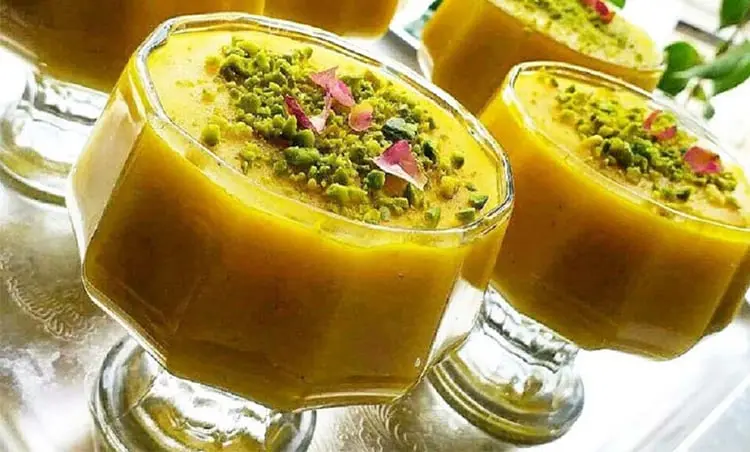 کاچی زعفرانی در ظرف‌های شیشه‌ای تزئین شده با پسته و گل خشک