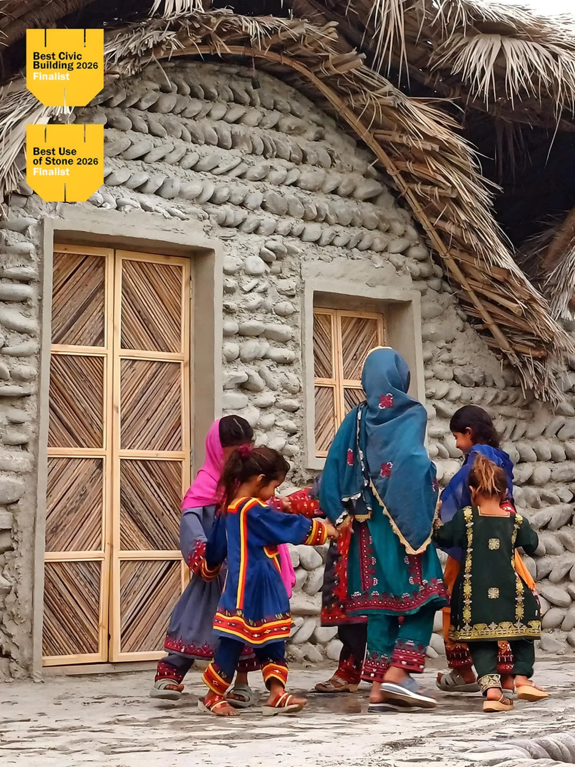 ساختمان سنتی با دیوارهای سنگی و سقف پوشالی در محیط روستایی